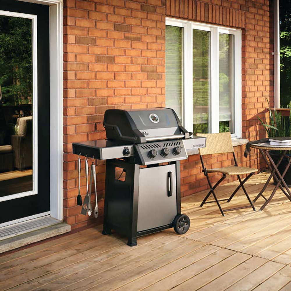 Gas grill on cart with closed lid and wheels on an outdoor patio