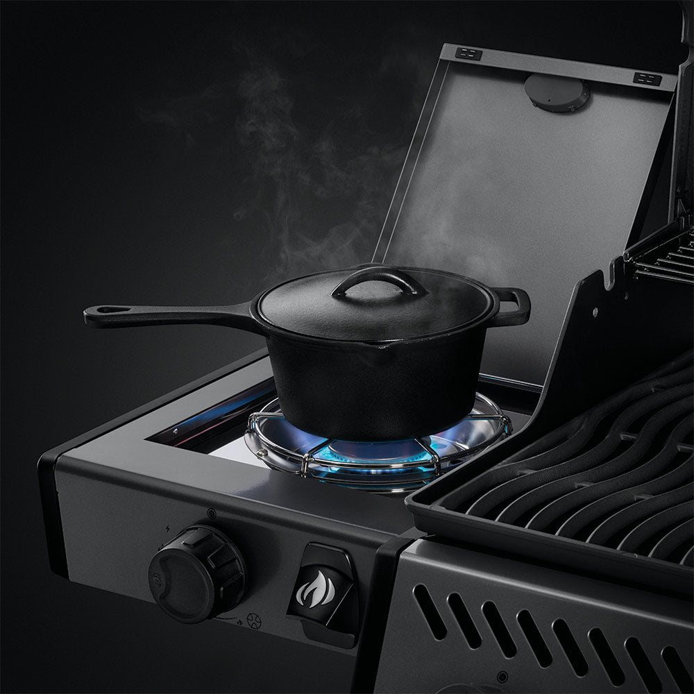 Gas grill side burner with pot heating over blue flame