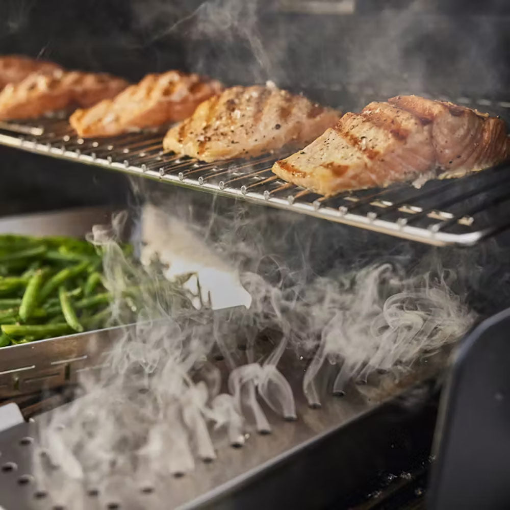 Gas grill with pan-seared meat and smoke rising from the grates