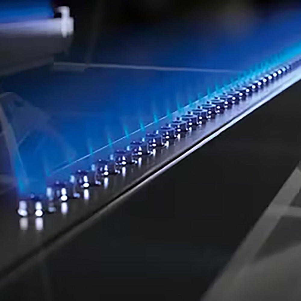 Gas grill burner tubes lit with blue flames inside the firebox