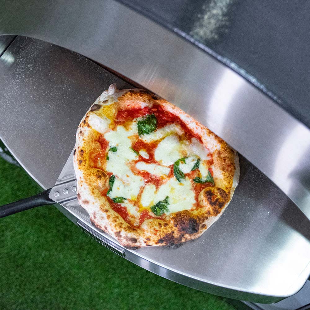 Gas pizza oven with a cheese and tomato pizza on a metal loading tray