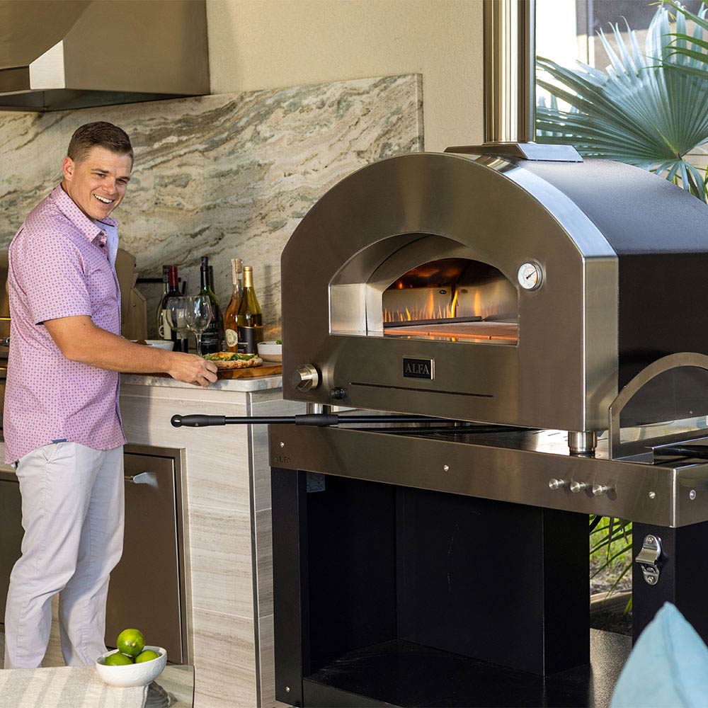 Stainless steel gas pizza oven with open arched front chamber and glowing burner flames