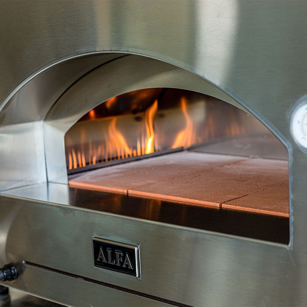Gas pizza oven interior with open flame and dark stone baking surface, ALFA badge