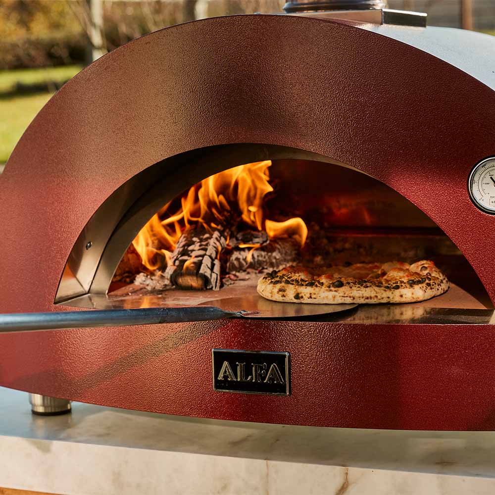 Red wood-fired pizza oven baking chamber with flames and a pizza on the stone