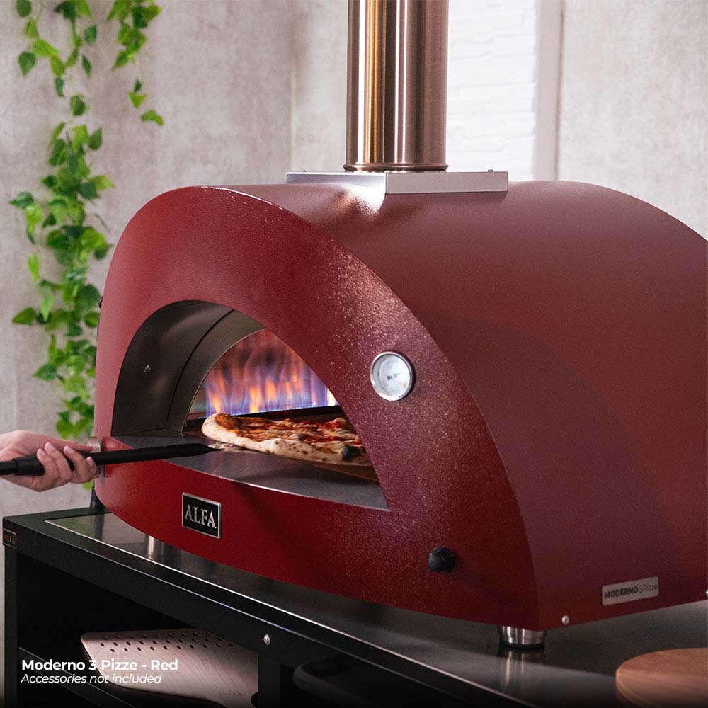 Ruby red gas pizza oven with lit flame in arched opening on black base