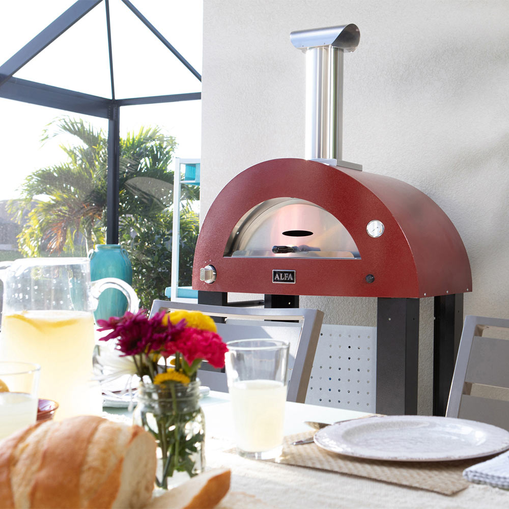 Ruby red freestanding gas pizza oven with arched bake chamber and flue chimney.