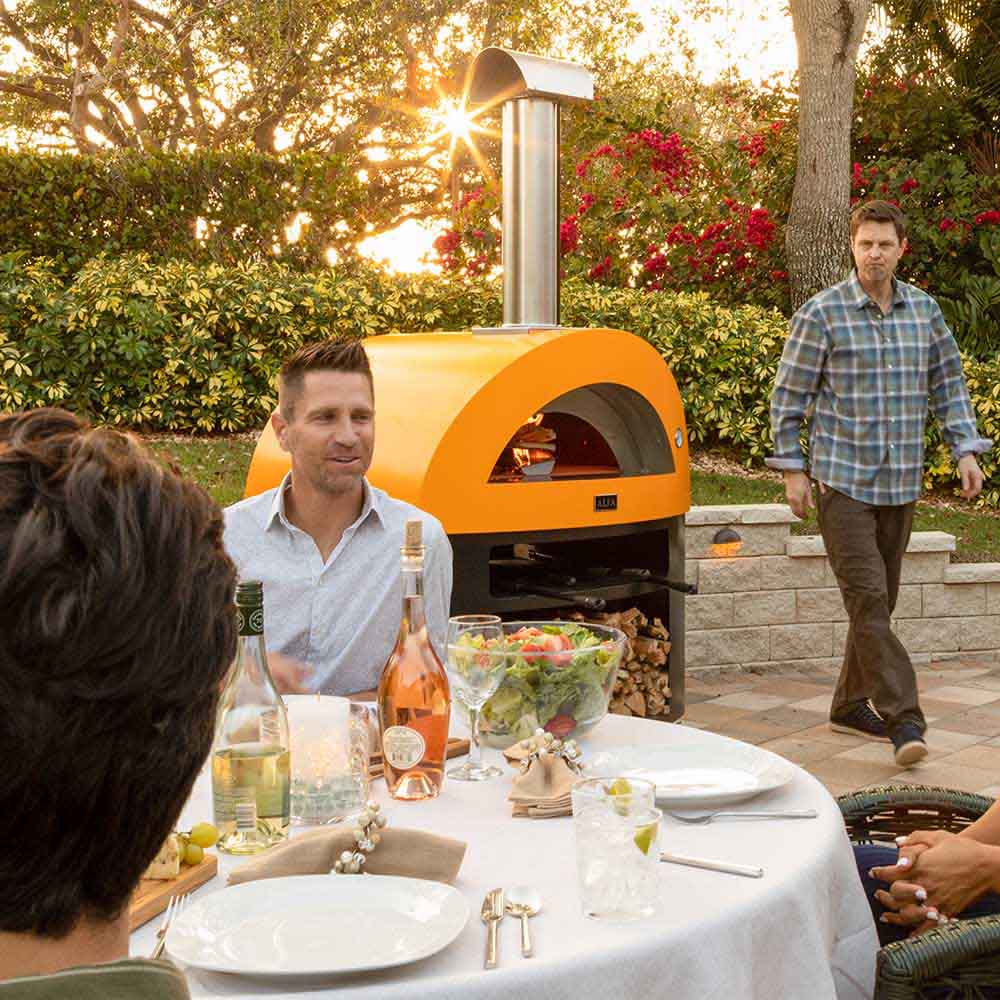 Freestanding wood-fired pizza oven with yellow dome, black base, and chimney