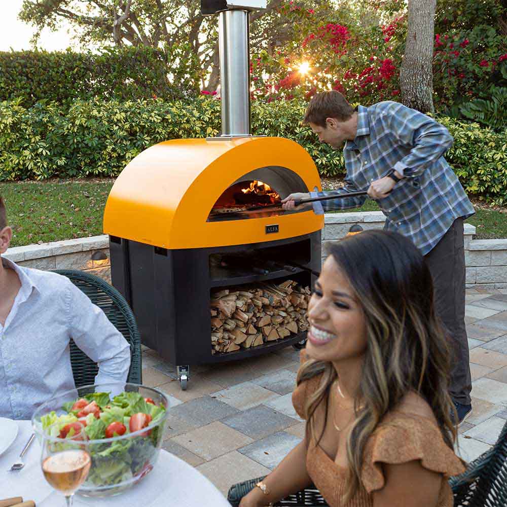 Freestanding wood-fired pizza oven with yellow dome and black firebox opening