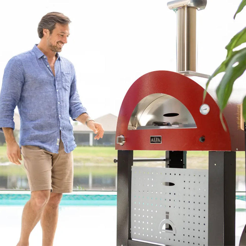 Red wood-fired pizza oven on wheels with chimney stack and arched front door