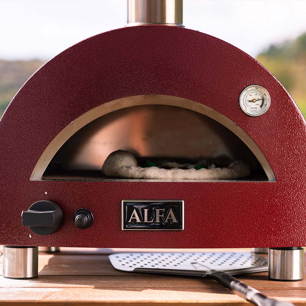 Portable gas pizza oven interior with red dome, stone hearth, pizza cooking