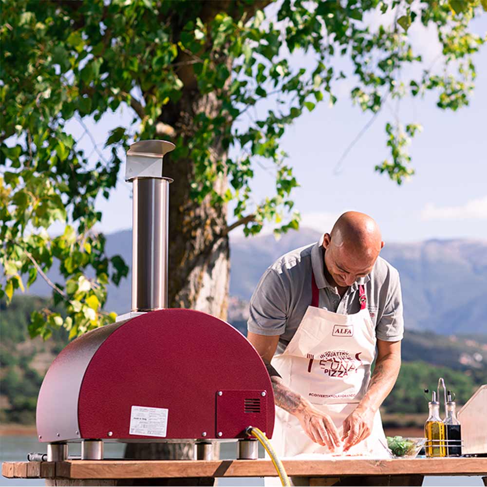 Portable gas pizza oven with red dome outdoors, chimney stack and control panel