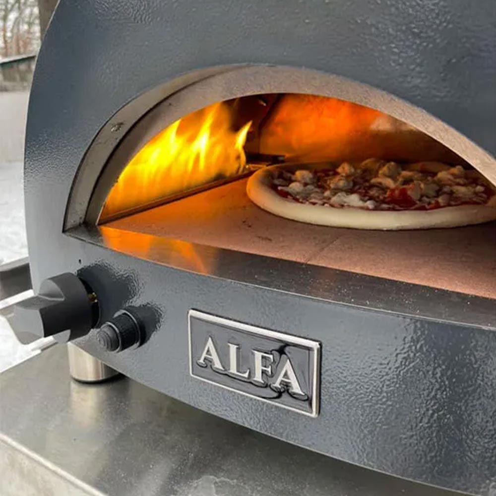 Gray portable gas pizza oven with open door, flames and pizza inside the hearth