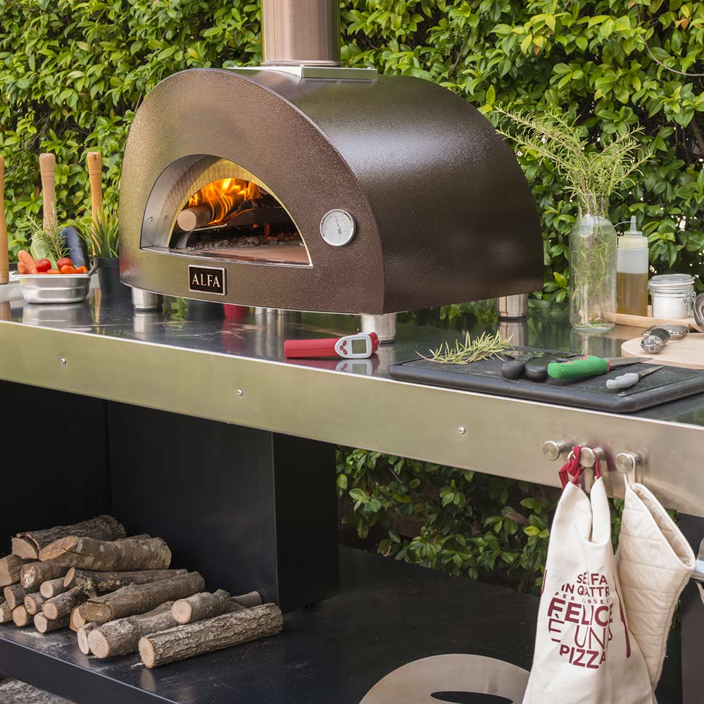 Wood-fired pizza oven with arched doorway, visible flames, stainless prep table