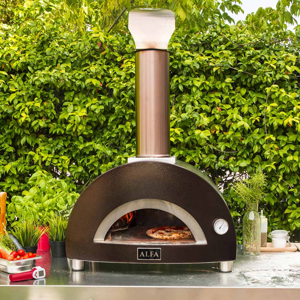 Wood-fired pizza oven on outdoor stainless counter with chimney and curved front door