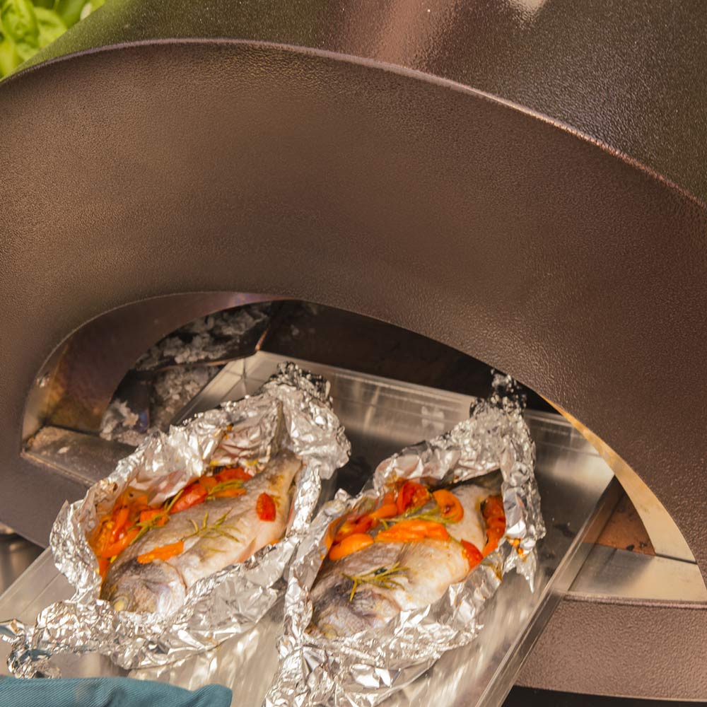 Close-up of wood-fired oven baking area with foil-wrapped food on the tray