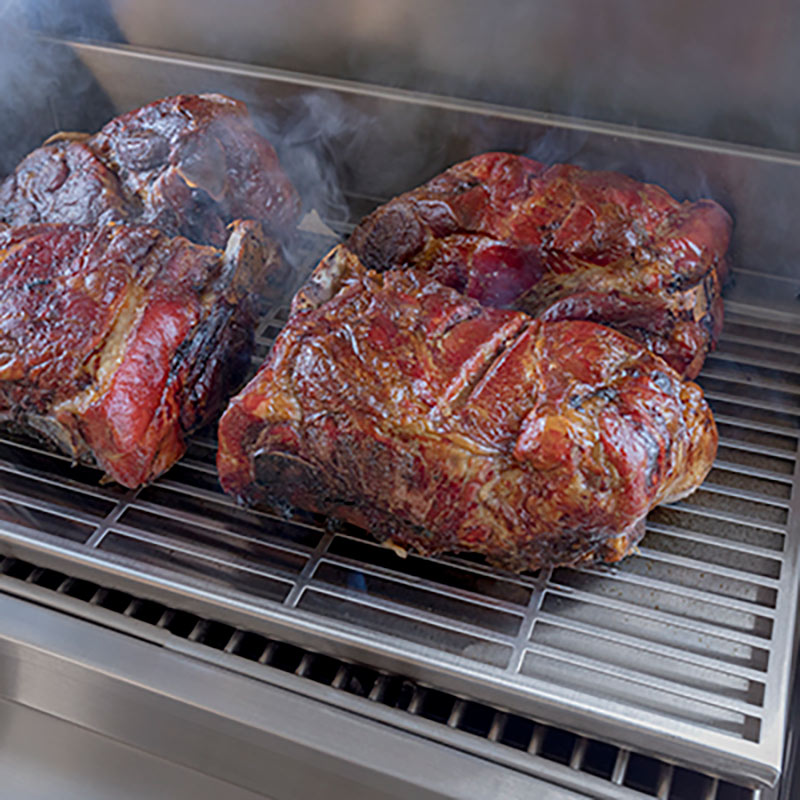 Infrared smoker roaster grate with grilled meat pieces on metal bars