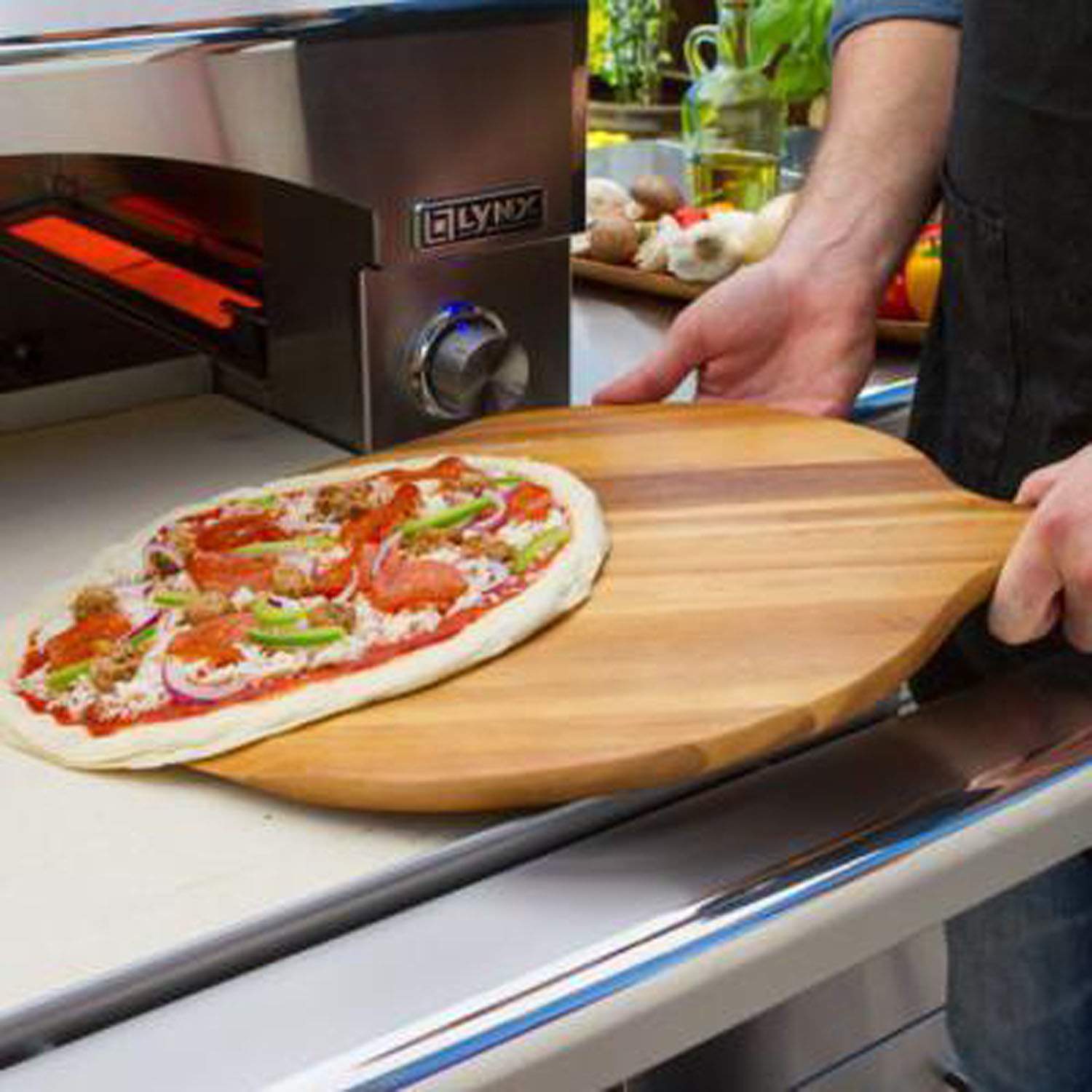 Pizza being placed onto the oven stone tray inside the pizza oven
