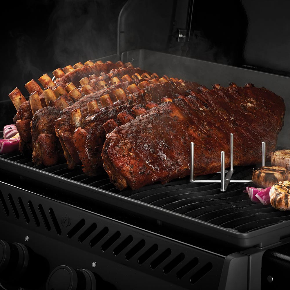 Rib rack on grill with multiple smoked ribs supported by metal rods