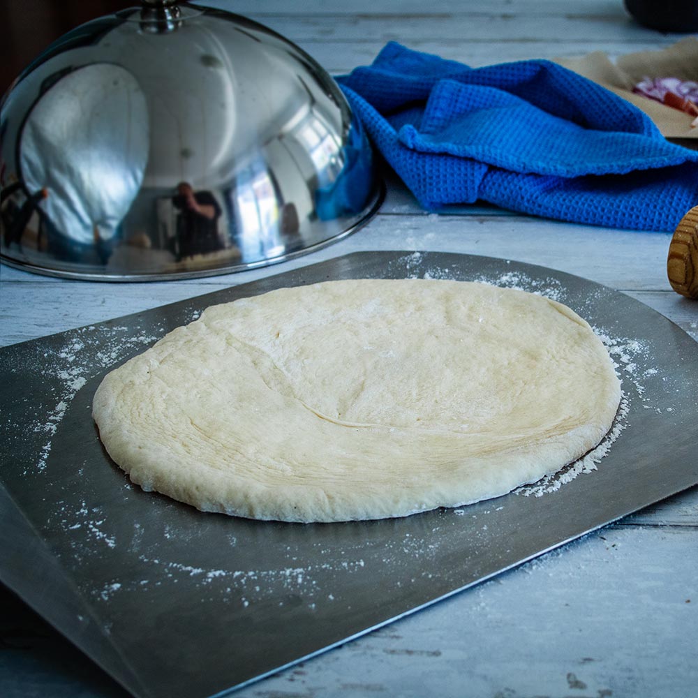 Stainless steel cooking dome lid beside flat dough
