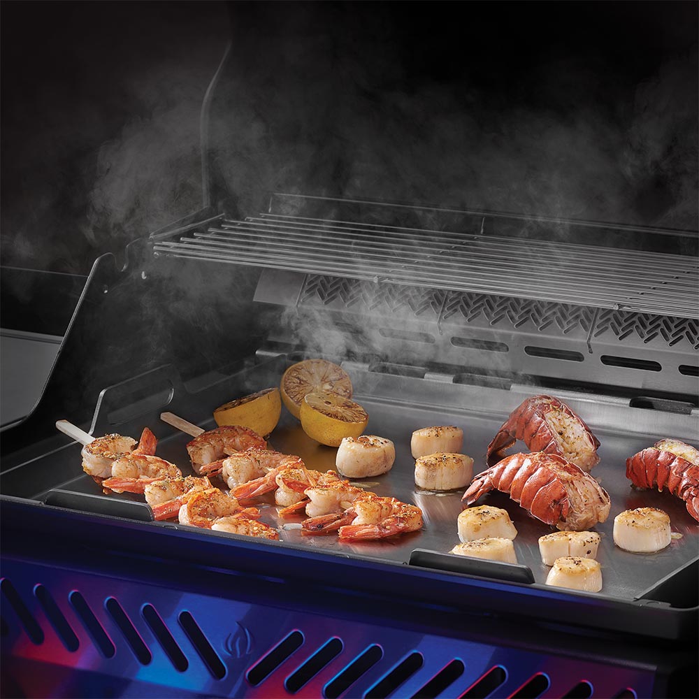 Stainless steel Napoleon griddle insert with grilled meat and vegetables