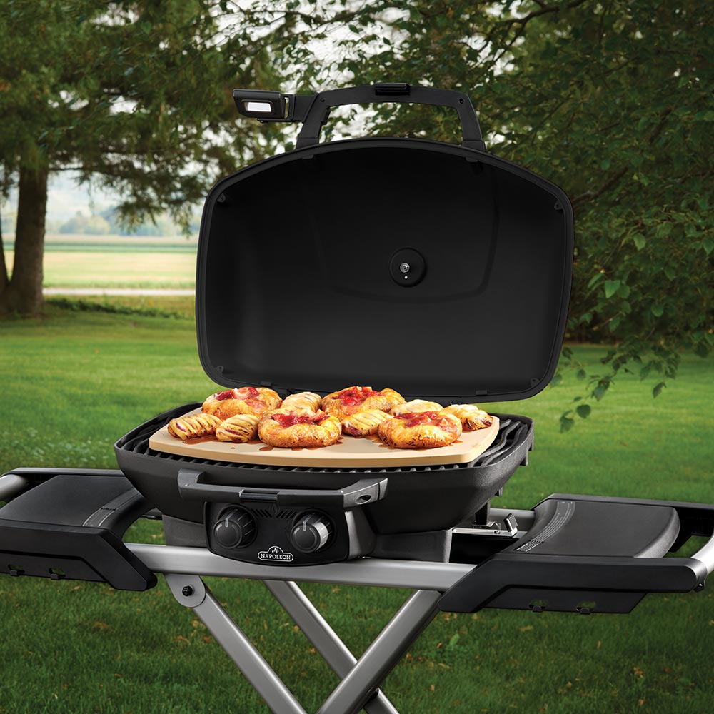 Pizza stone in open grill, mini pizzas on a light tan baking surface