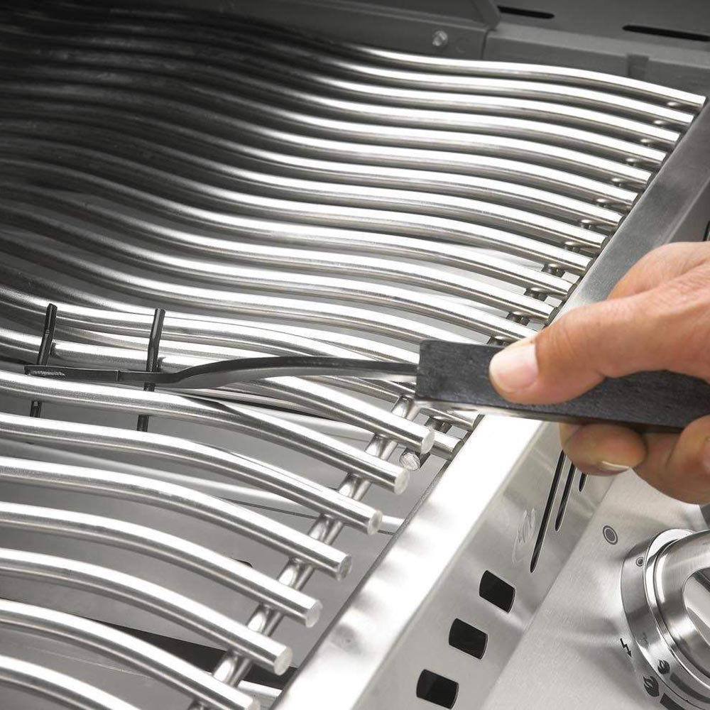 Metal grill grid lifter tool lifting grill grate bars on a cooking surface