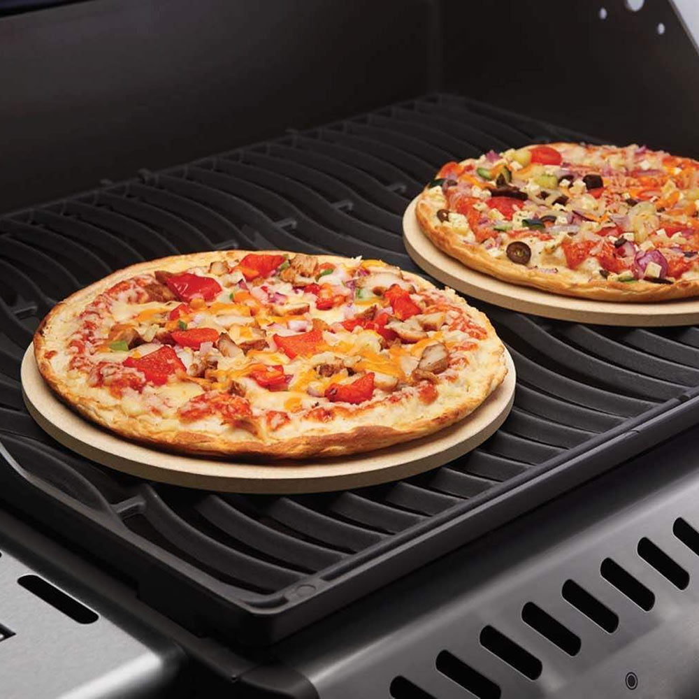 Pizza stones with two flatbreads on a gas grill grate