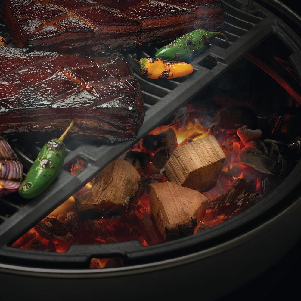 Gas grill with wood chunks and burning embers in the burner tray