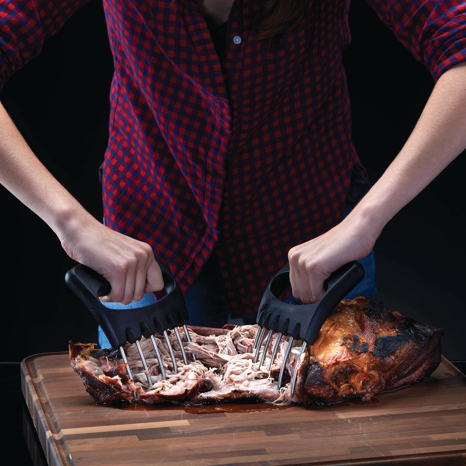 Handheld shredding claws with black handles used to pull apart cooked meat