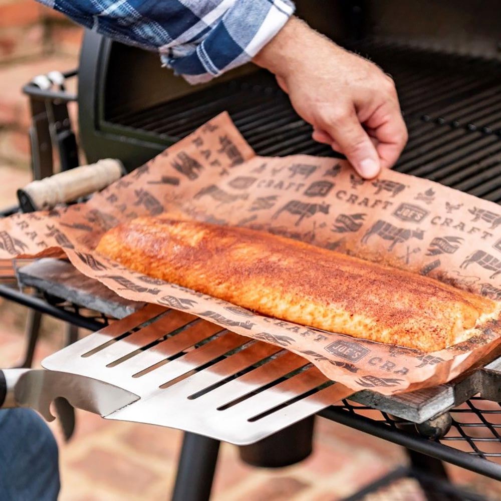 Slotted hawg lifter spatula lifting grilled meat from grill grate