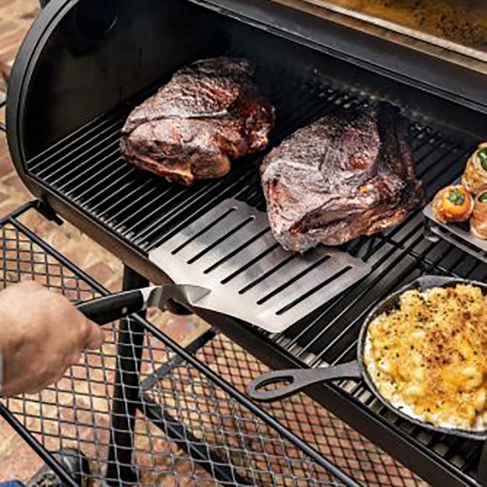 Hawg lifter spatula lifting food on a grill, with slotted metal head