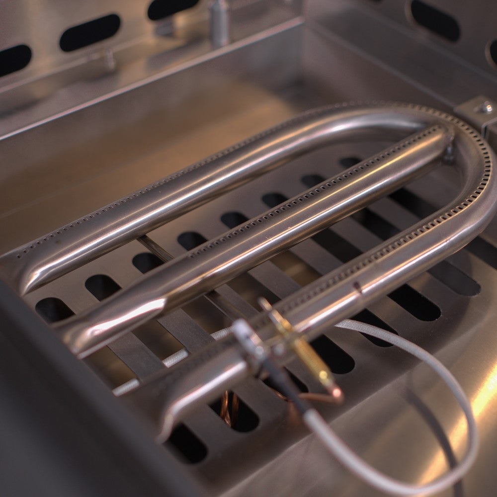 Close-up of gas griddle burner tubes and burner ports beneath the cooking surface