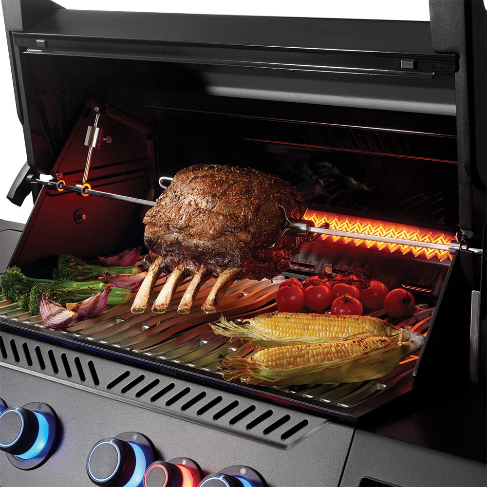 Napoleon gas grill interior with roasted chicken, corn, tomatoes, and vegetables on grates
