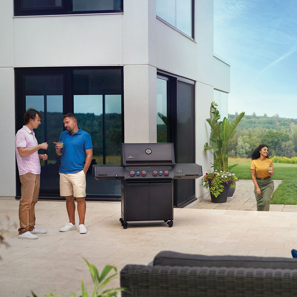 Napoleon Prestige gas grill on outdoor patio with people nearby