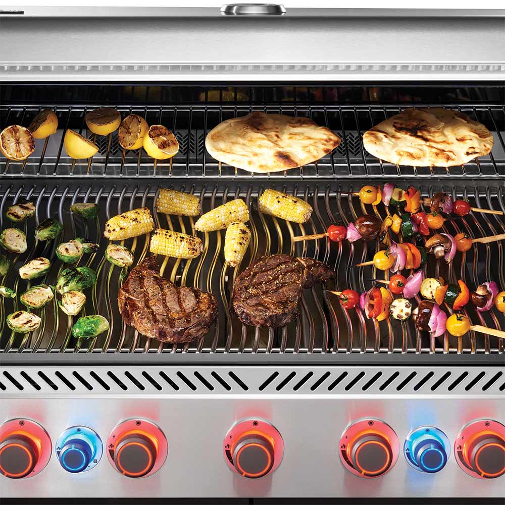 Gas grill cooking grates with vegetables, bread, and steaks; front control knobs with lights