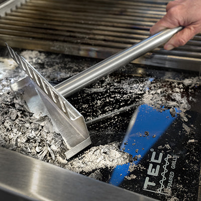Grill grate cleaning tool in use on grill grates with scraper head
