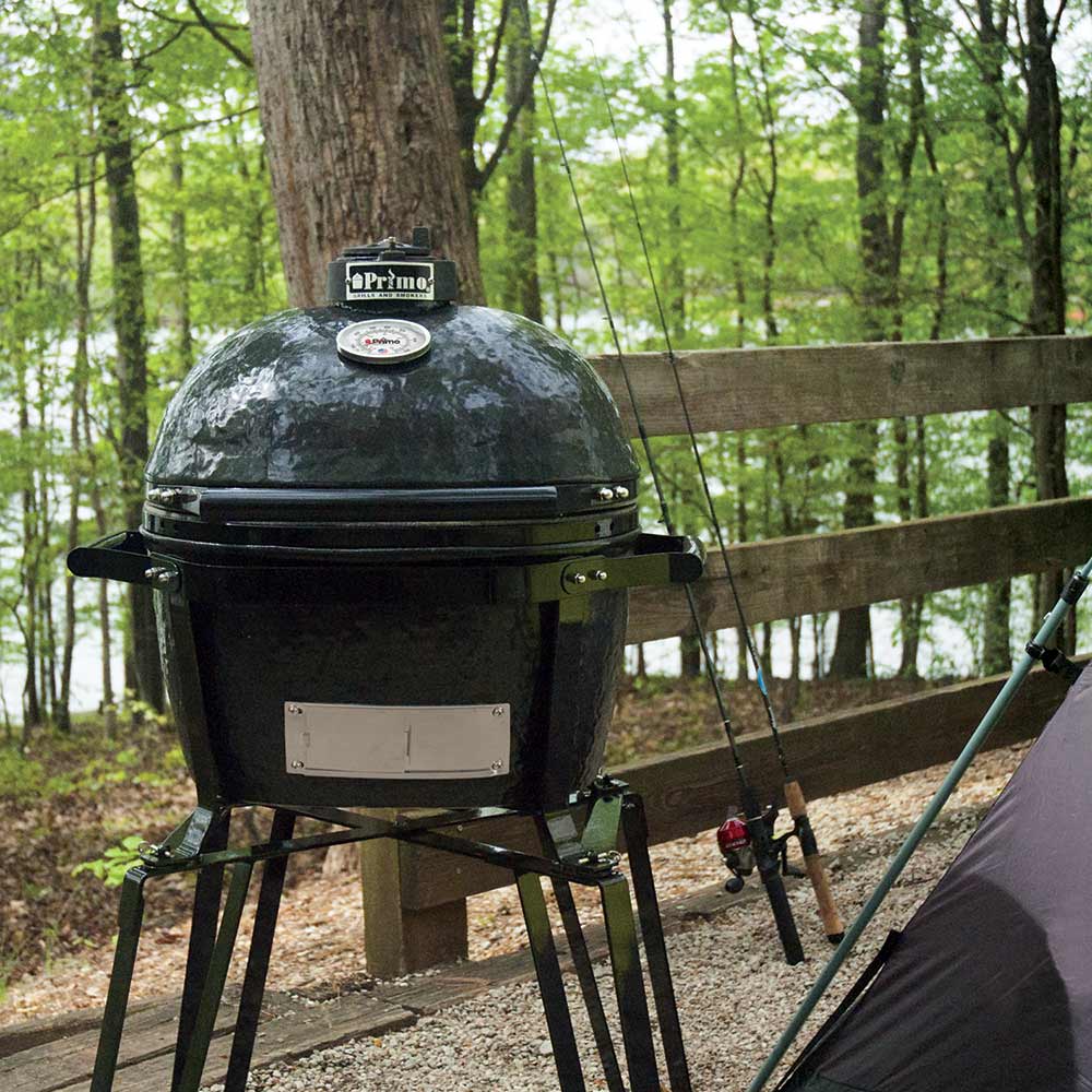 Junior oval ceramic kamado grill on portable metal cradle with vented lid.