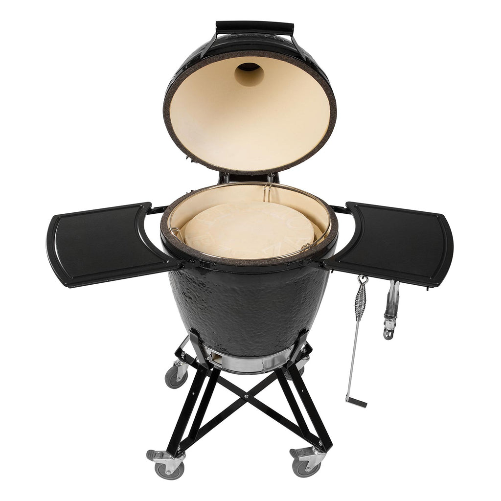 Black kamado grill with lid open, beige cooking chamber, side shelves, on wheels