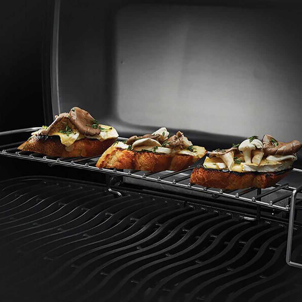 Portable grill with food on the grates and side drip tray, black burner box