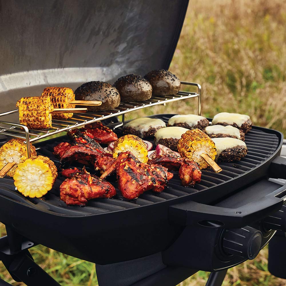 Portable grill with assorted kebabs and vegetables on the grate