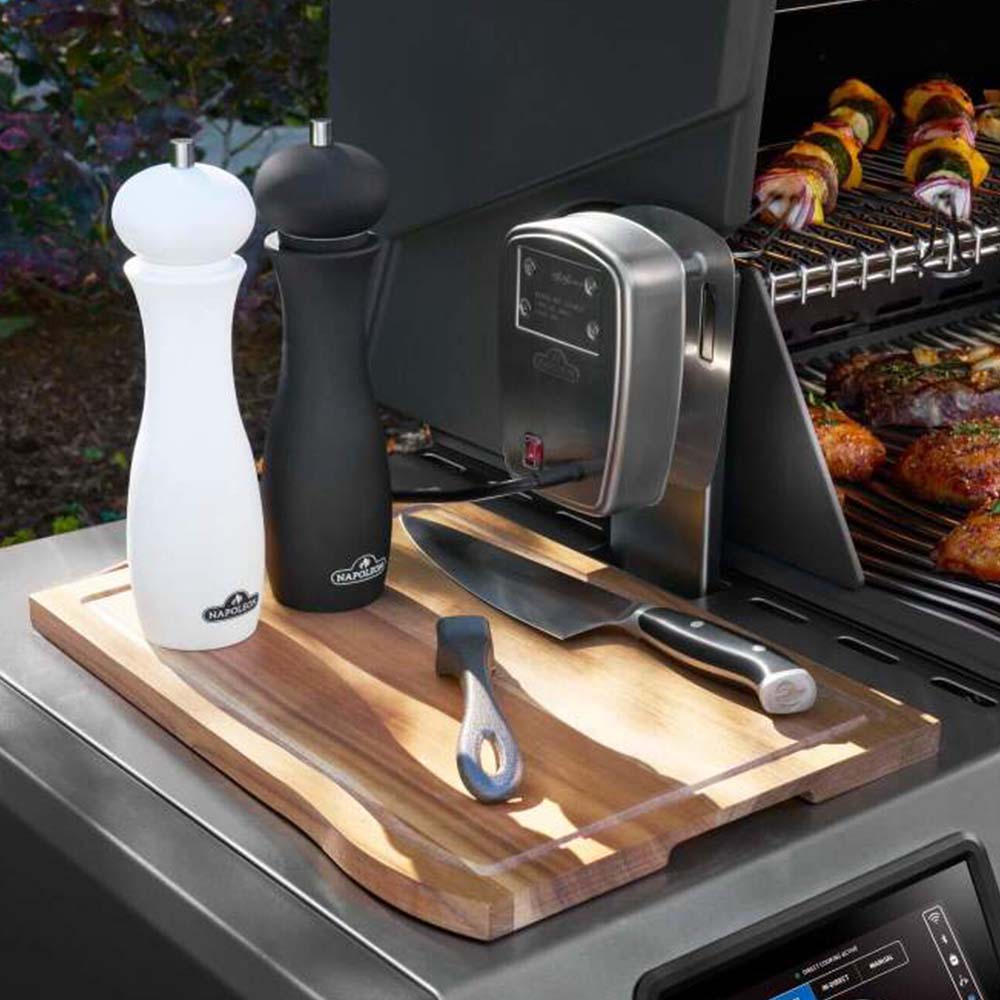 Stainless steel gas grill cooking surface with side shelf holding tools and seasonings