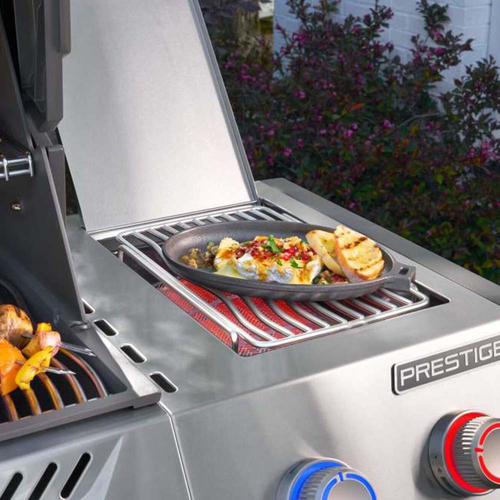 Stainless steel side burner grill insert holding a skillet with food