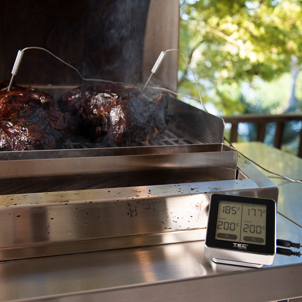 Wireless meat thermometer with dual probe leads and lit display showing temperatures