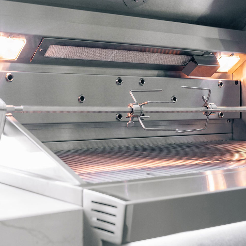 Stainless steel grill with open hood and rotisserie burner assembly above grates.