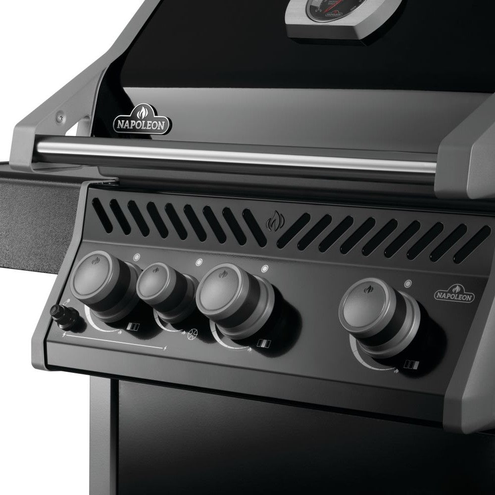 Gas grill control panel with four silver knobs and vented burner cover