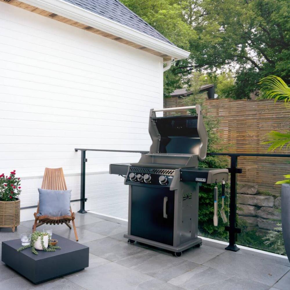 Black gas grill on patio with lid open and control panel, beside outdoor seating