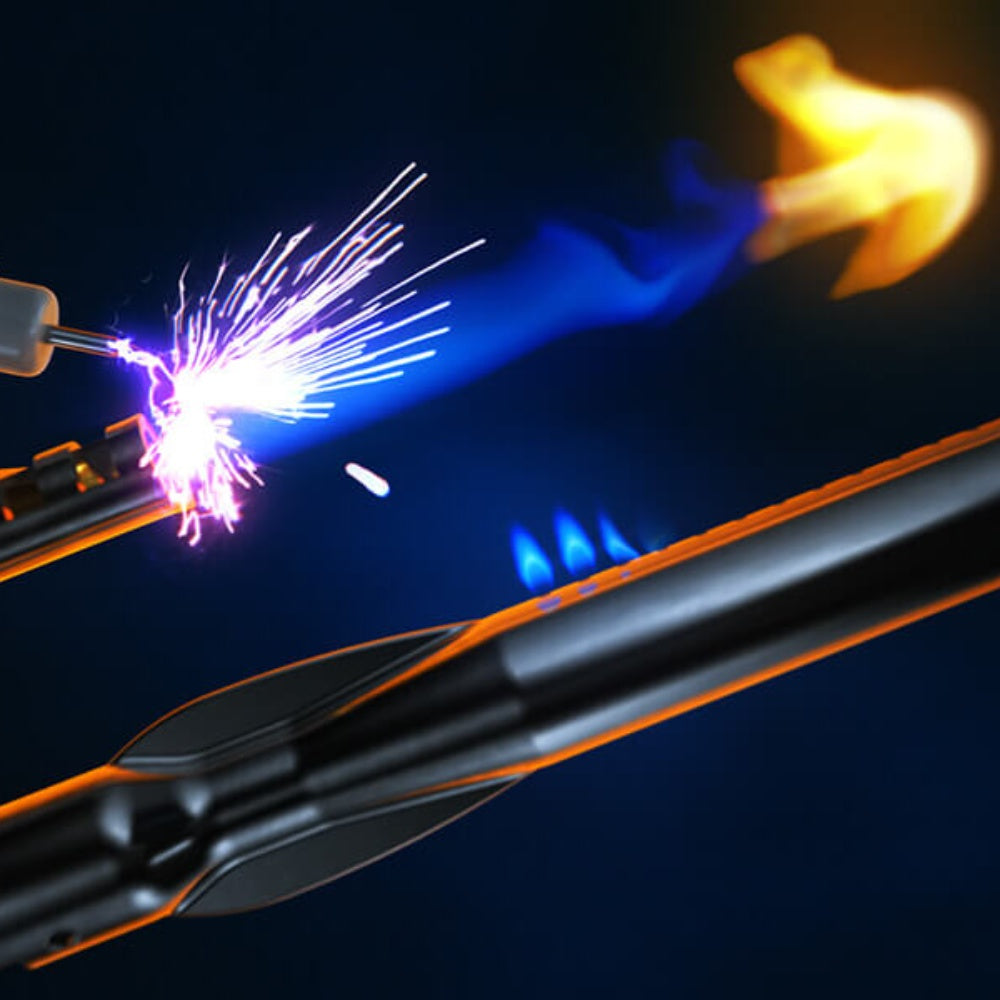 Gas grill burner igniting with visible flames and spark across the heating area