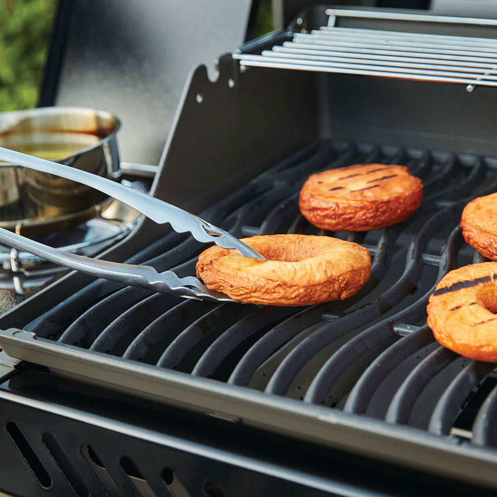 Gas grill grates with burgers and spatula, lid open