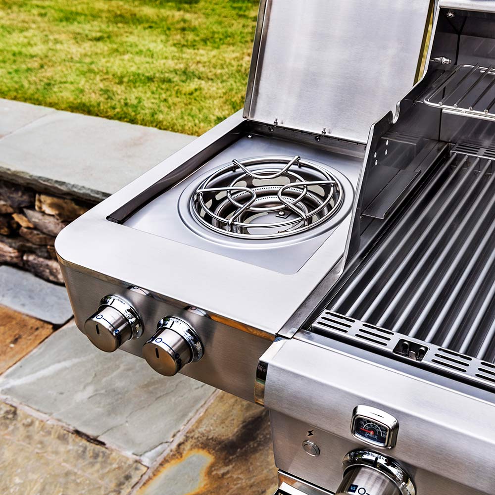 Stainless steel side burner with circular grate and control knobs on freestanding grill