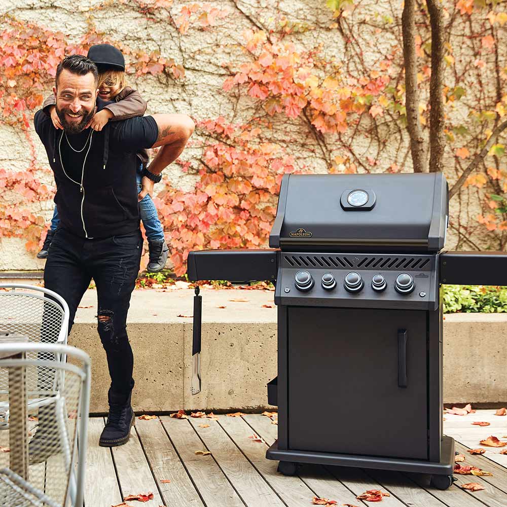 Black gas grill on cart with lid closed on outdoor wooden deck